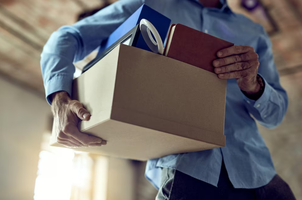 bottom side of the man in blue shirt holding a box of notebooks